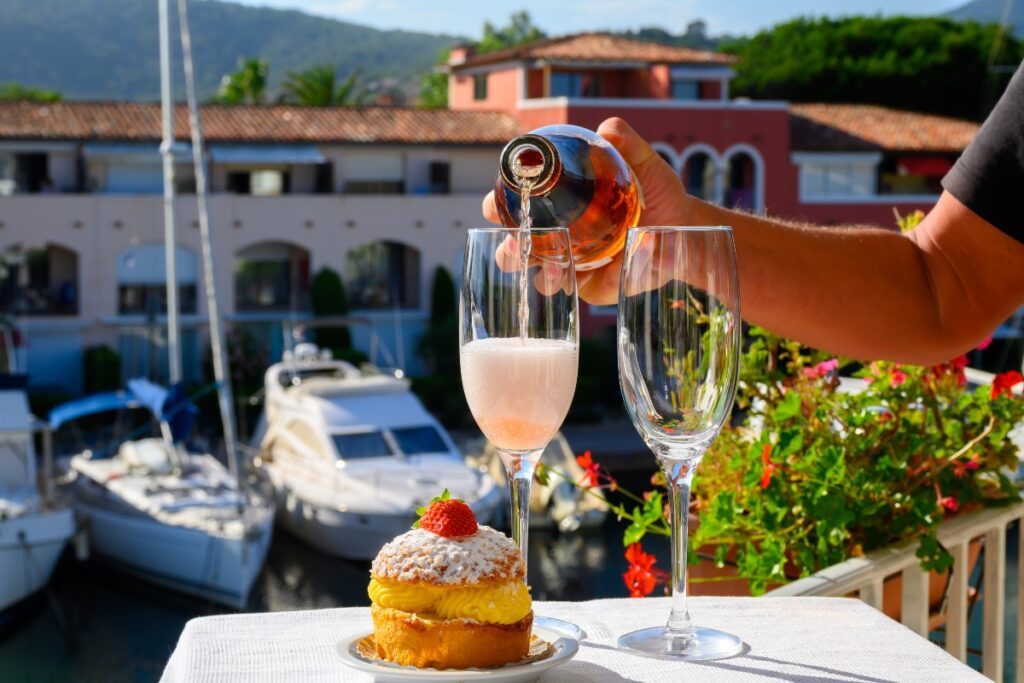deux flûtes de champagne et une tarte tropézienne sur une terrasse surplombant le port Grimaud